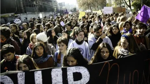 EPA Schoolchildren can be seen taking part in a march against sexism in Santiago