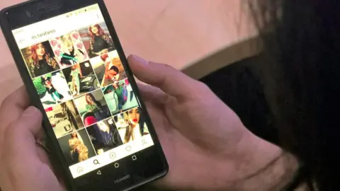 AFP A woman looks at the Instagram profile of Tara Fares in Baghdad on 28 September 2018