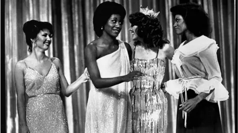 Getty Images Miss Arkansas, Lencola Sullivan (C) and Miss Washington, Doris Janell Hayes (far R) give each other a glance after they became the first two Black women ever to win first place in the Miss America pageant. Arkansas won the swimsuit division and Washington split first with Miss Oklahoma, Susan Powell (far L) in the talent division.