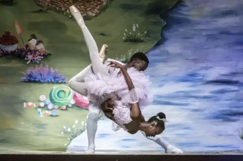 AFP A male and female ballet dancer perform a complex lift on stage.