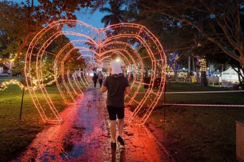 AFP People walk through a heart-shaped tunnel of red Christmas lights.