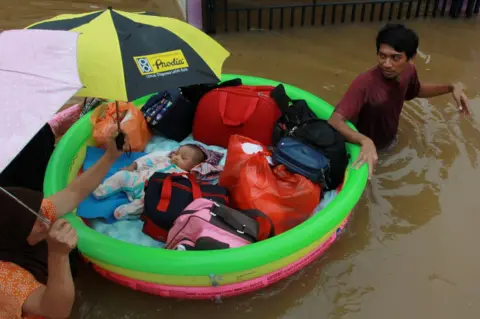 Muhammad Iqbal / Reuters A baby is rescued in an inflatable boat after floods hit a residential area in Tangerang, near Jakarta, Indonesia, 1 January 2020.