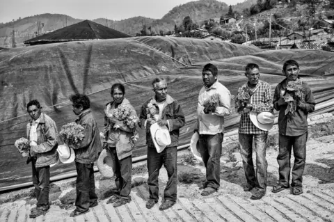 César Rodríguez A group of men offer flowers during a burial