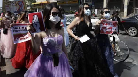 EPA Women dressed in ball gowns hold up placards as they march during a protest against the military coup, in Yangon, Myanmar, 10 February 2021.