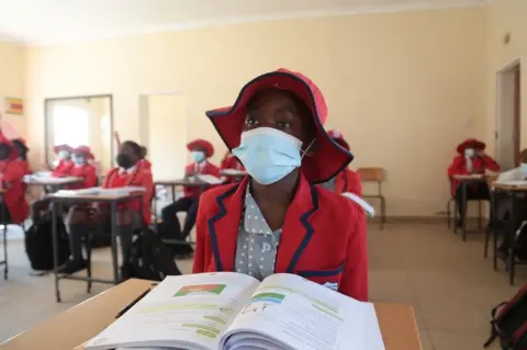 EPA A student wears a face mask as she attends a lesson at the Oceanwaves Junior School just outside Harare, Zimbabwe, 30 August 2021. Schools have in Zimbabwe reopened for examination writing classes only after four months of a forced closure due an upsurge in the number of COVID-19 cases