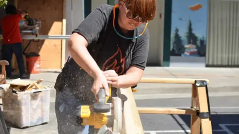 Project Ember woman sawing wood