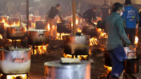 Reuters People overseeing many pots cooking over open fires in Cape Town, South Africa - Monday 2 May 2022