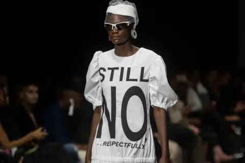 Getty Images A model in a dress with the words "Still No... Respectfully" taking part in the South African Fashion Week Spring/Summer 2022 Collection, Johannesburg, South Africa - Friday 29 April 2022