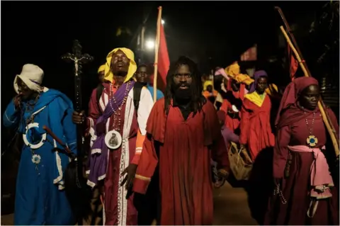 AFP Worshippers of the Legio Mary walking on a procession overnight. They are wearing religious clothing and have rosaries and crucifixes.