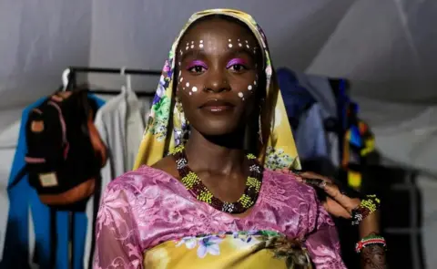 Reuters A woman wearing putple and white makeup with a head covering posing for a photo.