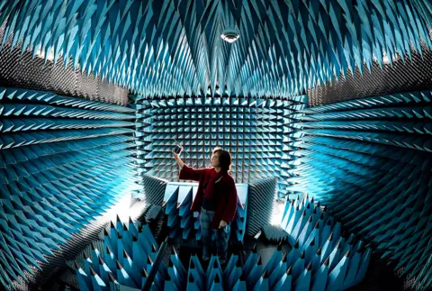 Simon Hulme Professor Fun Hu inside Bradford University's "anechoic chamber", holding a "pocket cube" satellite
