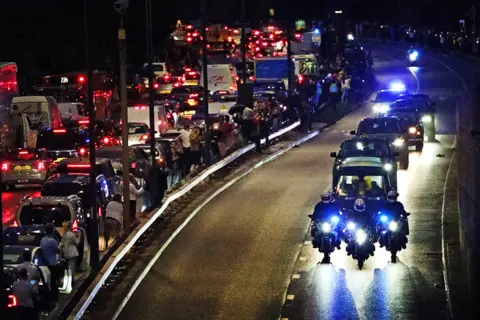 Victoria Jones People get out of their cars to watch as the hearse carrying the coffin of Queen Elizabeth II passes along the A40 in west London, 13 September 2022