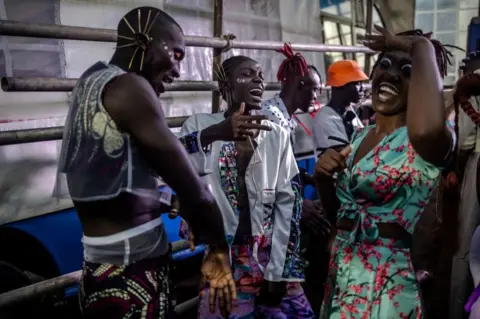 LUIS TATO/AFP Models dance and sign during a break at the backstage of main show of the Kibera Fashion Week in the informal settlement of Kibera in Nairobi, on October 15, 2023. Kibera Fashion Week is a platform created from the community to redefine fashion and creativity while showcasing beauty and talent as a way to change the narrative about Nairobi's largest informal settlement.