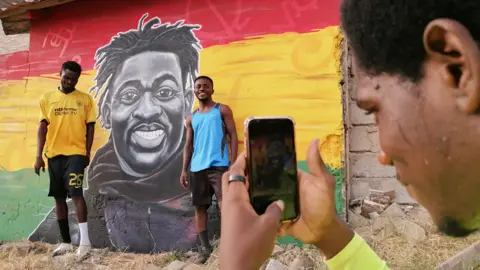 Kwame Adzaho-Amenortor/Getty Images Footballers having their photo taken in front of a mural of Christian Atsu at at Awudu Issaka Park, Tema, Ghana - Friday 24 February 2023