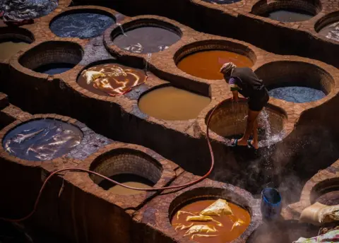 Jasmine Leung/Getty Images A worker cleans himself at a tannery within the medina of Fes, Morocco - 3 April 2023