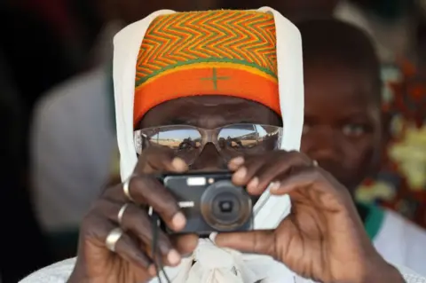 AFP A man takes a picture during the inauguration ceremony of the solar energy power plant in Zaktubi, near Ouagadougou, on november 29, 2017, on the second day of France's President Emmanuel Macron first African tour since taking office.