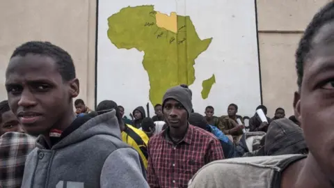 AFP A picture taken on November 27, 2017 shows African migrants waiting outside in a courtyard at the Tariq Al-Matar detention centre on the outskirts of the Libyan capital Tripoli.