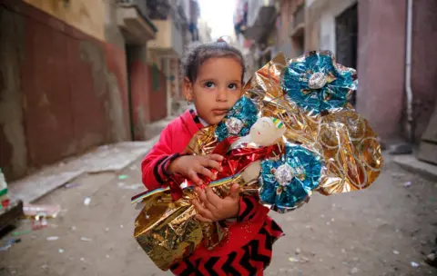 Reuters Habiba, 6, hugs Aroset El Moulid or (Bride of Moulid) traditional sugar candy in the shape of dolls, in preparation for the celebration Prophet Muhammad"s birthday, in Tanta, north of Cairo, Egypt November 24, 2017. Picture taken November 24, 2017.
