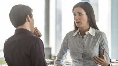 Getty Images Man and woman talking in an office