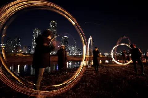 YONHAP/ EPA People participate in jwibulnori, a popular game for celebrating the first lunar full moon of the new year