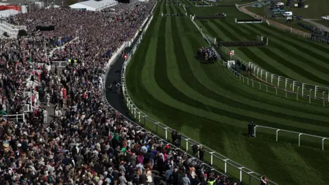 EPA Riders compete in the William Hill Top Price Guarantee Handicap Hurdle Race during the Randox Grand National Festival at Aintree Racecourse in Liverpool. The picture is looking down a long straight with huge crowds off to the left.