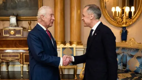 AFP/Getty Images Britain's King Charles III (L) shakes hands as he welcomes Canada's Prime Minister Mark Carney ahead of an audience at Buckingham Palace, in central London, on March 17, 2025. 
