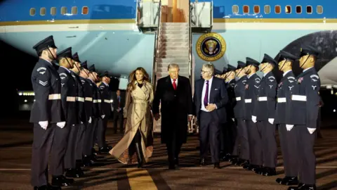 Reuters President Trump and Melania Trump's welcoming line-up on the runway at Stansted airport