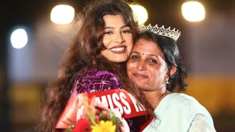 Muskan Sharma Miss Rishikesh 2025 Muskan Sharma poses hugging her mother who's wearing her crown. "The crown is as much hers as it's mine. She taught me to stand up for what's right. Without her I wouldn't be the person I am today."