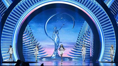 Getty Images Women in silver mini dresses standing on the Miss Universe stage