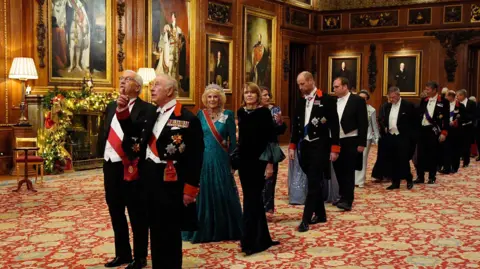 PA Media The guests stand in pairs in a long queue in an ornate room in Windsor Castle